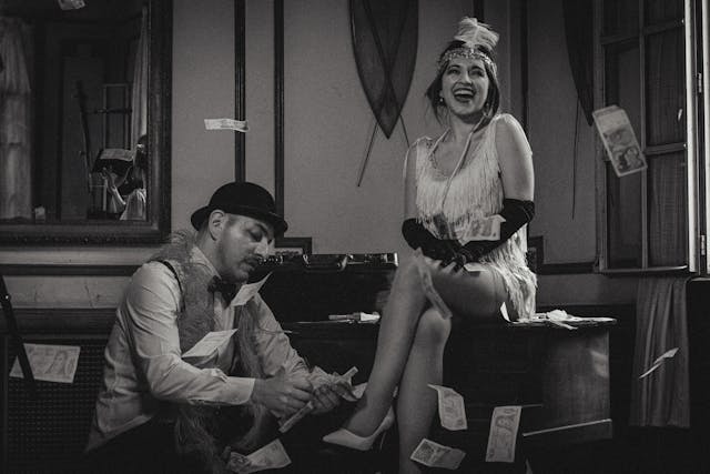 flapper girl sitting atop a piano with a man playing it