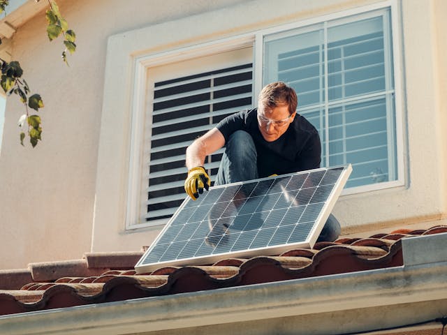 man installing sun panels on a roof